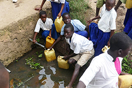Schulkinder in Tansania legen teils weite Wege zurück um verschmutztes Wasser aus offenen Wasserstellen zu holen, aus denen auch Tiere trinken.